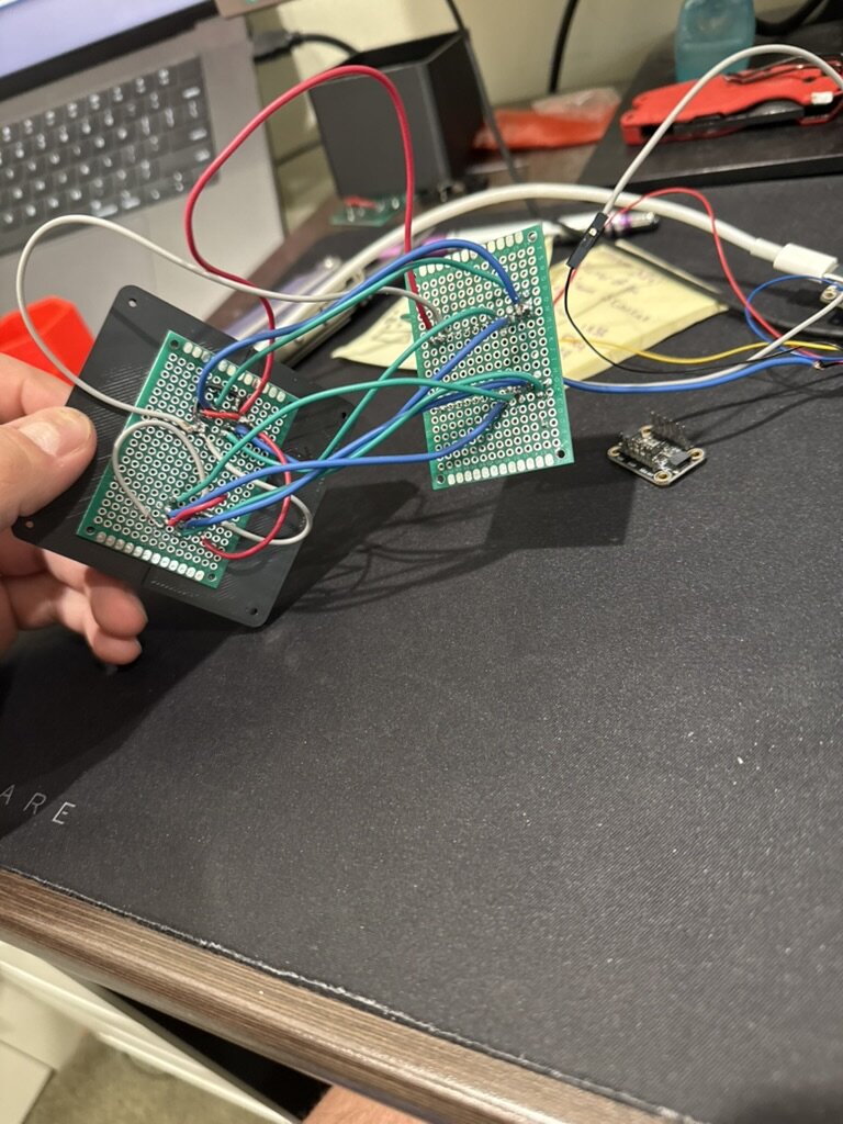 Two protoboards wired together, held over the desk